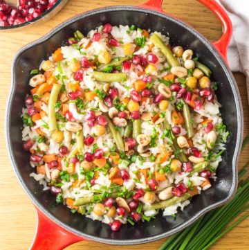 Arroz salteado colorido numa frigideira vermelha de ferro fundido