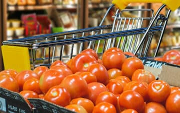carrinho de compras no supermercado por trás de uma bancada de tomates